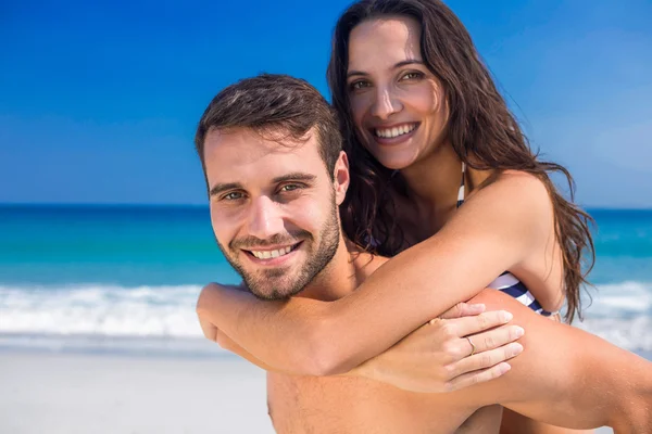 Uomo dando maialino torna alla sua ragazza in spiaggia — Foto Stock
