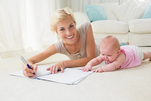 Mutter mit Baby schreibt an Textbuch — Stockfoto