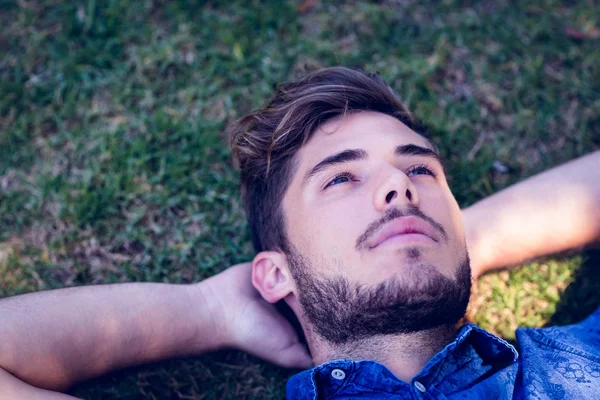Młody człowiek w pozycji leżącej w parku — Zdjęcie stockowe