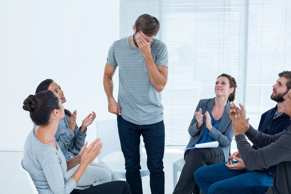 Grupo de rehabilitación aplaudiendo al hombre encantado de pie — Foto de Stock