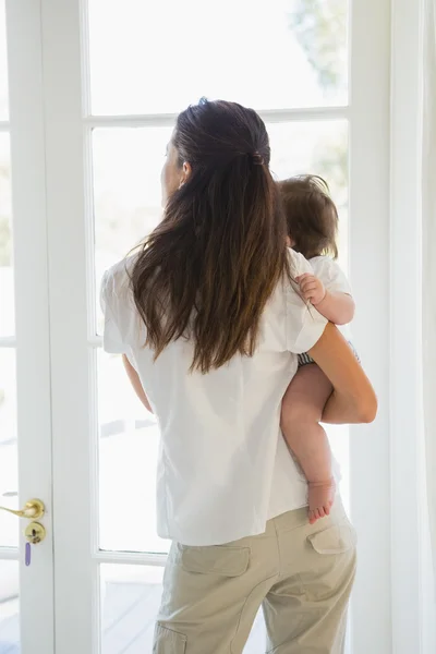 Madre con bebé niña mirar hacia fuera en casa —  Fotos de Stock