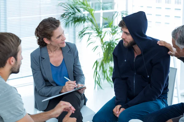 Betrokken man troostend andere in rehab groep — Stockfoto