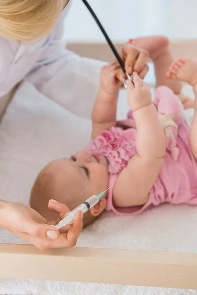 Baby girl and doctor using syringue and needle — Stock fotografie