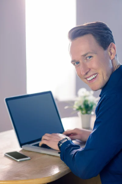 Zufriedener Geschäftsmann mit seinem Laptop, der in die Kamera lächelt — Stockfoto