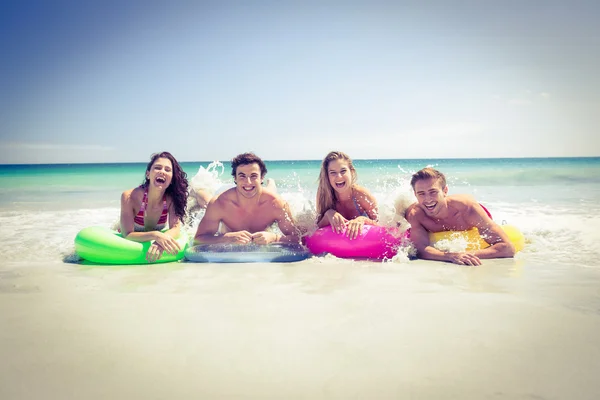 Happy friends lying on inflatable mattress above the water — Stock Photo, Image