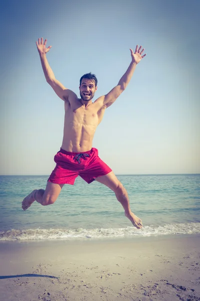 Glücklicher Mann springt an den Strand — Stockfoto
