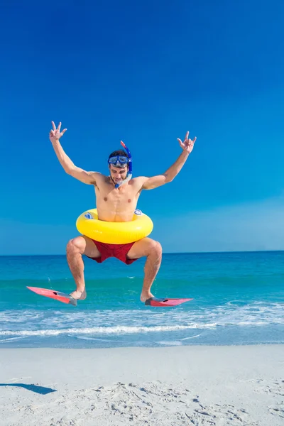 Man met flippers en rubberring op het strand — Stockfoto