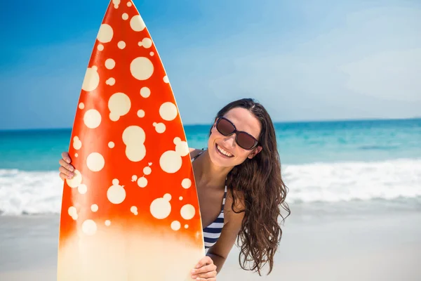 Pretty brunette with a surfboard looking at camera — Stockfoto