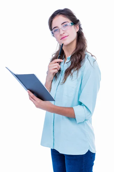 Doordachte geeky hipster met een pen tegen haar kin hij controleren — Stockfoto