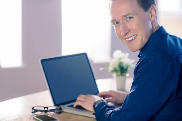 Zufriedener Geschäftsmann mit seinem Laptop, der in die Kamera lächelt — Stockfoto