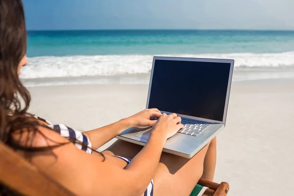 Pretty brunette using laptop on deck chair — Stock Photo, Image