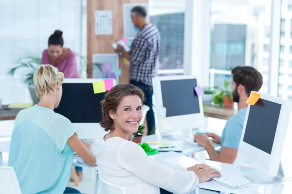 Lächelnde junge Frau bei der Arbeit mit ihrem Kollegen am Schreibtisch — Stockfoto