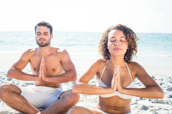 Pareja feliz haciendo yoga al lado del agua — Foto de Stock