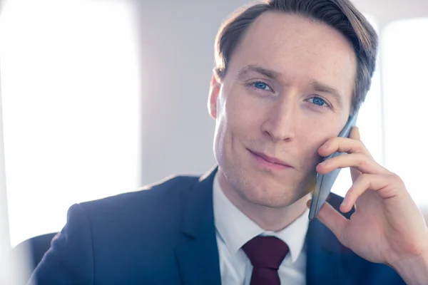 Уверенный бизнесмен смотрит в камеру во время телефонного звонка — стоковое фото
