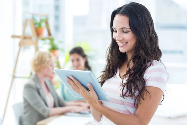 Smiling businesswoman using a tablet with colleagues — Stock Photo, Image
