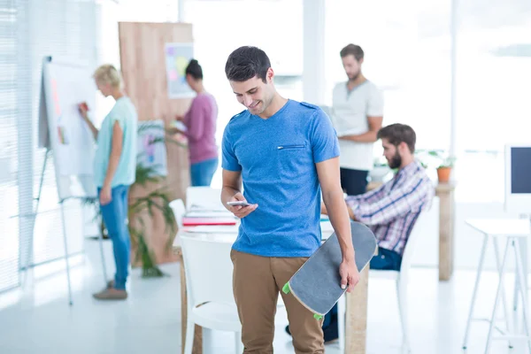 Businessman holding a skateboard in the office — Stock Photo, Image