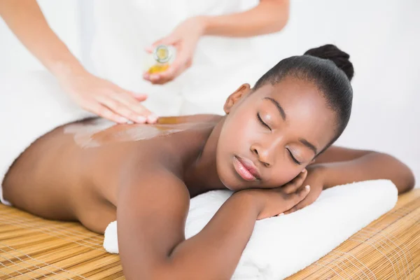 Massa massagista derramando óleo de massagem na mulher — Fotografia de Stock