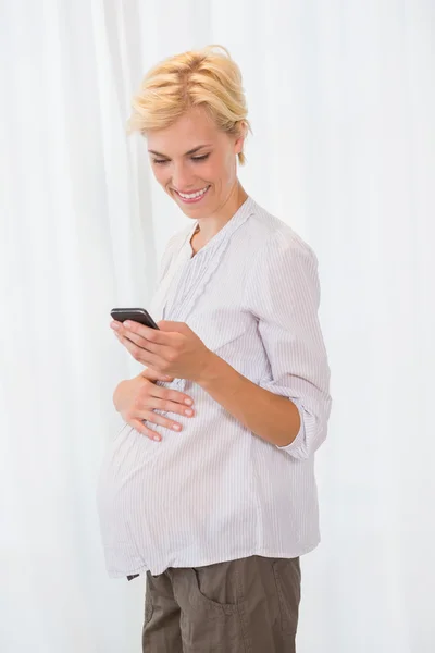 Blondine schwanger mit ihrem Handy — Stockfoto