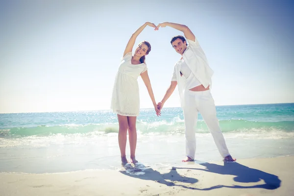 Casal feliz formando forma de coração com as mãos — Fotografia de Stock