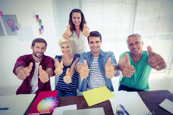 Feliz equipe de negócios criativa gesticulando polegares para cima — Fotografia de Stock