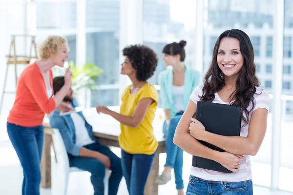 Smiling businesswoman with colleagues in background at office — Stock Photo, Image