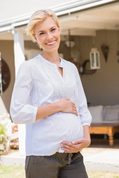 Блондинка с беременными руками на животе — стоковое фото