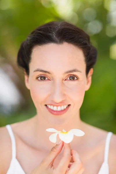 Feliz morena sosteniendo una flor blanca — Foto de Stock