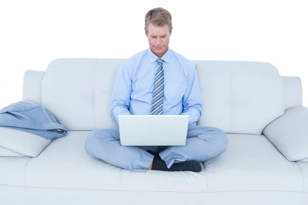 Hombre de negocios guapo sentado en el sofá usando su computadora portátil —  Fotos de Stock