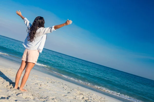 Happy woman with arms outstretched at the beach — Stockfoto