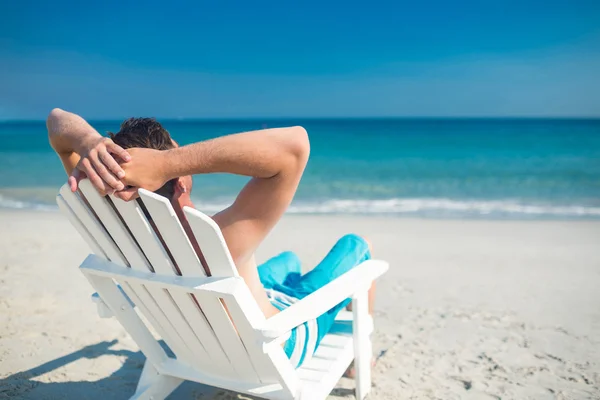 Hombre relajante en la silla de cubierta en la playa — Foto de Stock