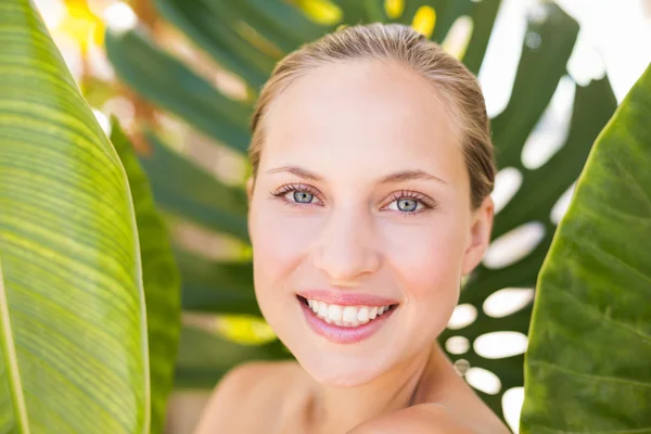 Belle blonde souriante à la caméra derrière la feuille — Photo