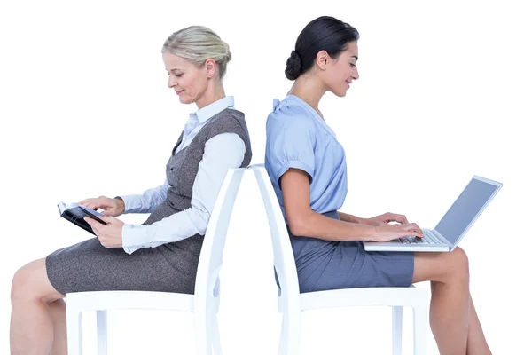 Businesswomen using laptop and reading book — Stock Photo, Image