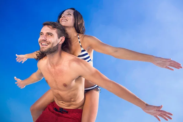 Hombre dando cerdito de nuevo a su novia en la playa —  Fotos de Stock