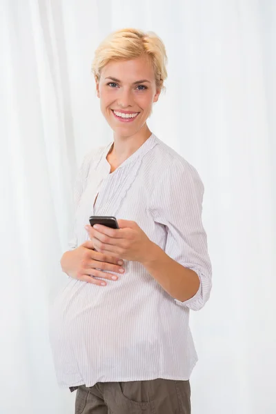 Loira grávida usando seu celular — Fotografia de Stock