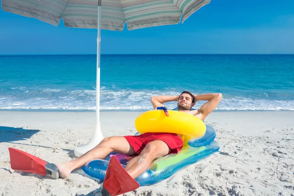 Homem deitado na praia com nadadeiras e anel de borracha — Fotografia de Stock