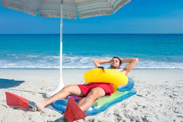 Man lying on the beach with flippers and rubber ring — 图库照片