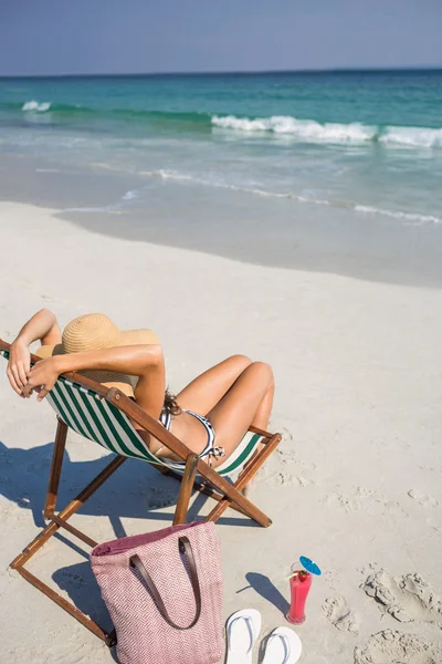 Vista trasera de la bonita morena relajándose en la tumbona en la playa —  Fotos de Stock