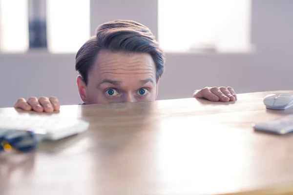 Nervoso homem de negócios espreitando sobre a mesa — Fotografia de Stock