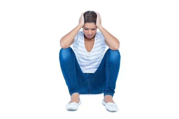 Brunette zittend op de vloer met hoofdpijn — Stockfoto