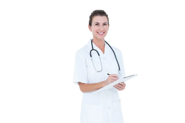 Doctor smiling and holding clipboard — Stockfoto