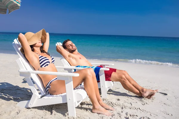 Happy couple relaxing on deck chair at the beach — Stock Photo, Image