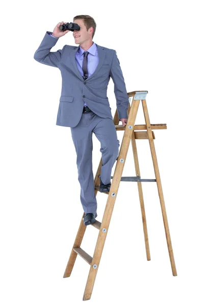 Businessman using binoculars while climbing on ladder — Stock Photo, Image