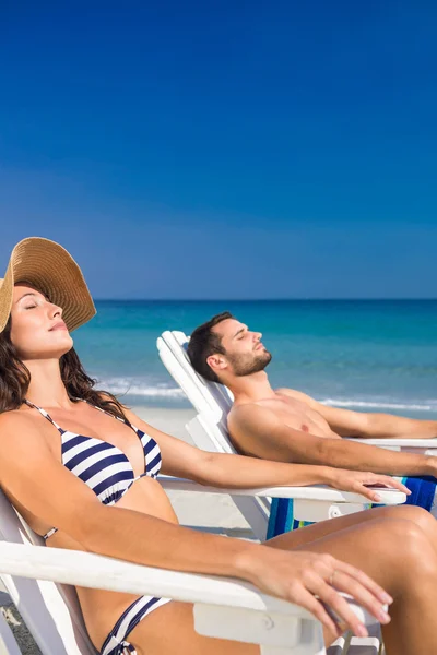 Happy couple relaxing on deck chair at the beach — Stockfoto