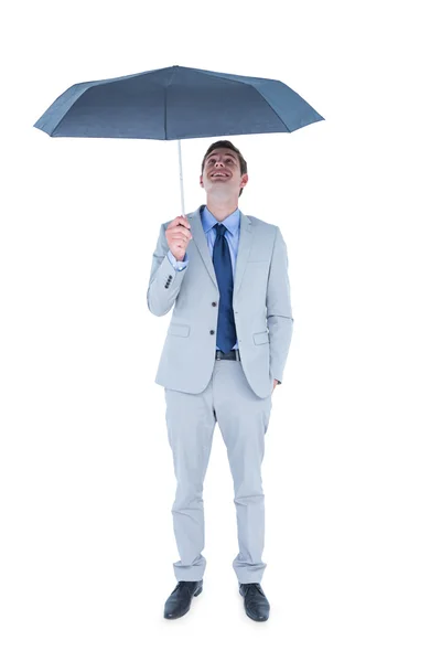 Businessman sheltering under umbrella — Stock Photo, Image