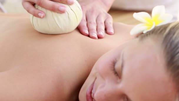 Vrouw genieten van een kruiden comprimeren massage — Stockvideo