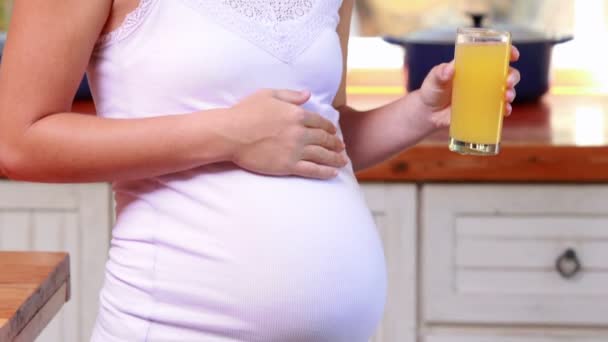 Mujer embarazada bebiendo un vaso de jugo de naranja — Vídeo de stock