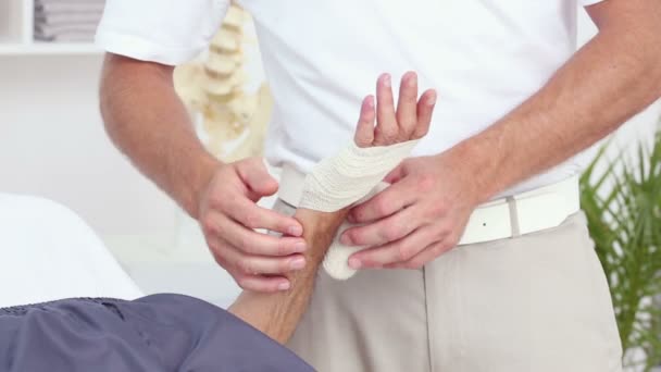 Doctor bandaging his patients hand — Stock Video