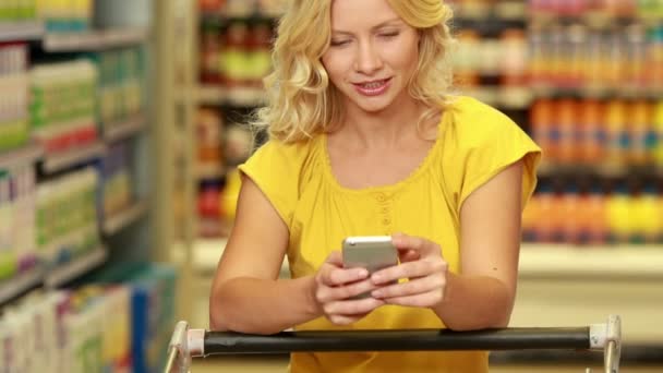 Blonde faire un appel téléphonique tout en faisant du shopping — Video