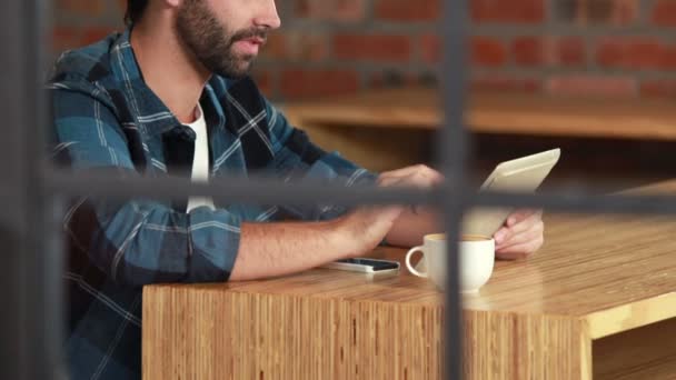 Hipster hombre usando una tableta y sorbiendo café — Vídeos de Stock