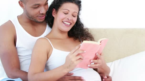Schwangere und ihr Mann lesen ein Buch — Stockvideo
